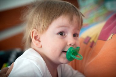 Saçları dağınık ve emzik ile tapılası bir çocuk neşeli bir ruh ve oyuncu bir merak sergileyerek, canlı çevrelerini keşfeder..