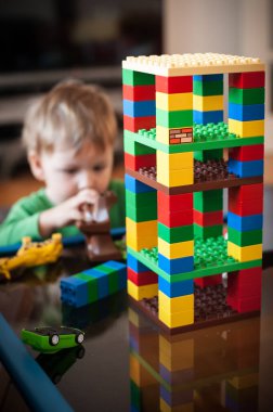 Genç bir çocuk yapı taşlarını kullanarak canlı bir kule inşa ederek yaratıcı bir oyun oynar. Neşeli atmosfer yaratıcı keşiflerin bir anını yakalıyor..