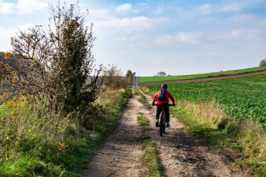Toprak yolda bisiklet süren bir adam.