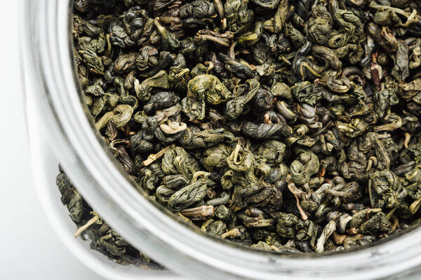 Сухие листья зеленого чая в банке крупным планом.
