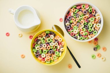 Sarı arka planda renkli mısır halkaları. Halka şeklinde, sütlü kahvaltı gevreği..