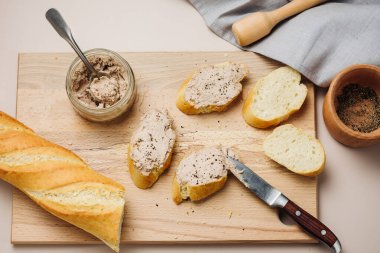 Baguette with homemade beef liver pate on a cutting board.