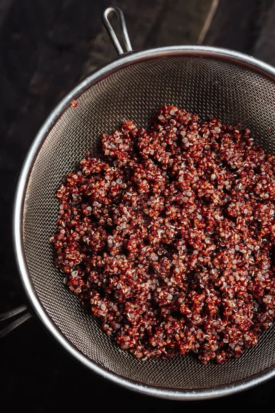 Cooked organic red quinoa in a sieve.
