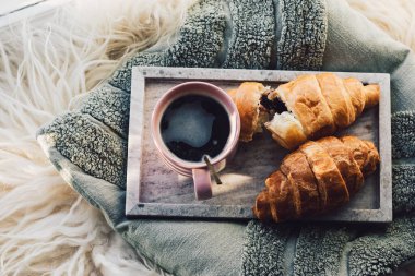 Tepside çikolatalı kruvasan olan bir fincan kahve..