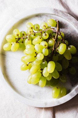 Bir demet yeşil-beyaz sultana üzümü mermer tepside.