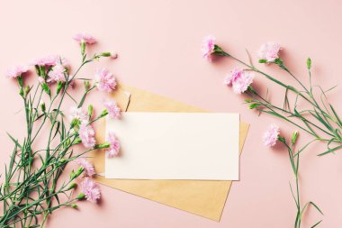 Boş tebrik kartı ve pembe arka planda güzel karanfil çiçekleri..