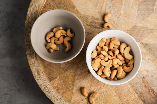 Roasted cashew nuts in a bowl on a wooden tray.