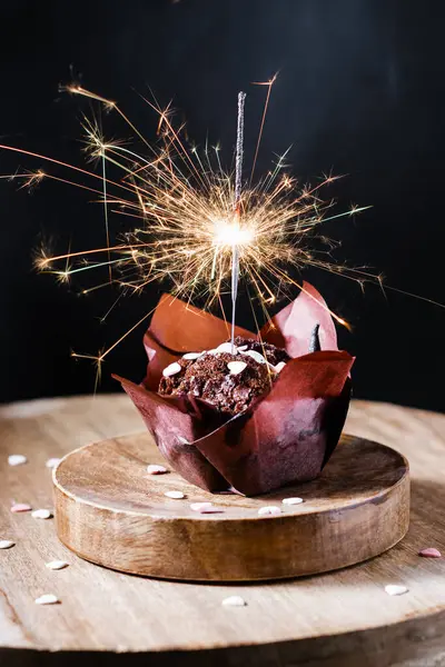 Festive chocolate muffin with sparkler on a dark background.