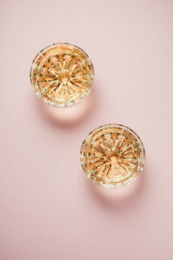 Pembe arka planda iki bardak beyaz şarap..