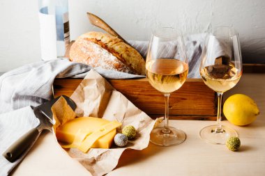 Masada iki bardak beyaz şarap, peynir ve ekmek..