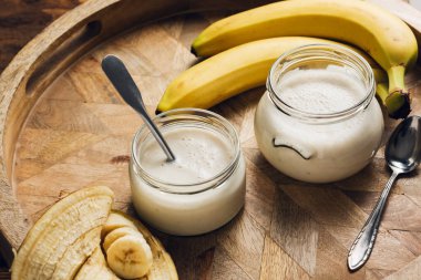 Tahta tepside iki kavanoz muzlu yoğurt.