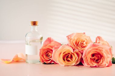 Güller ve bir şişe gül kokulu su, gerekli yağ. Aromaterapi, spa konsepti.