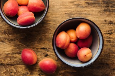 Ahşap masa üzerinde kase taze kayısı.