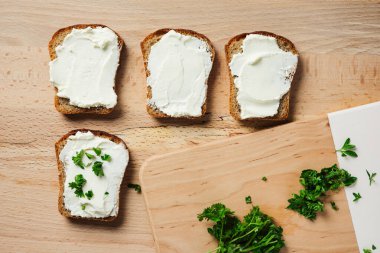 Krem peynirli tostlar ahşap masada, üst manzara.