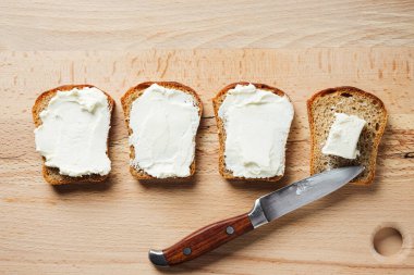 Krem peynirli tostlar ahşap masada, üst manzara.