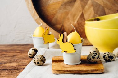 Paskalya masa dekorasyonu. Yakın plan. Sarı mum yumurta, tavşan ve bıldırcın yumurtası..