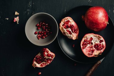 Koyu arkaplanda bir kasede taze kesilmiş nar..