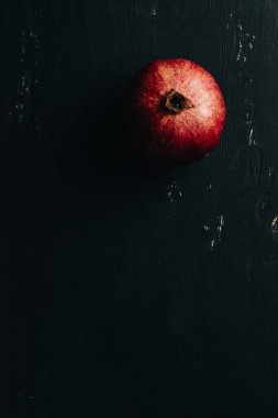 Siyah ahşap zemin üzerinde nar, üst görünüm.