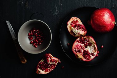 Koyu arkaplanda bir kasede taze nar..