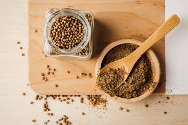 Ahşap bir masada tüm ve zemin kişniş tohumları.