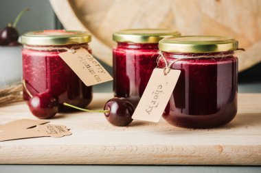 Masadaki küçük kavanozlarda tarçın ve ev yapımı kiraz reçeli..