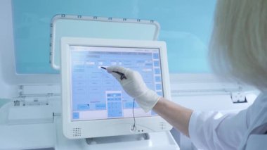 Test tüpleri olan laboratuvar test makinesi ve bilgisayar üzerinde veri ayarlayan laboratuvar asistanı.