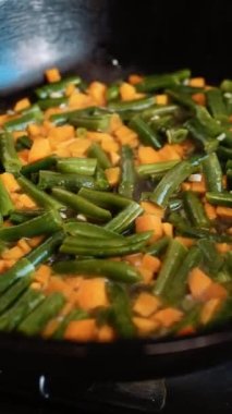Kızartma tavasında haşlanmış sebze. Yemek pişirmek. Sağlıklı yiyecekler. Yeşil fasulye ve havuç. Dikey video