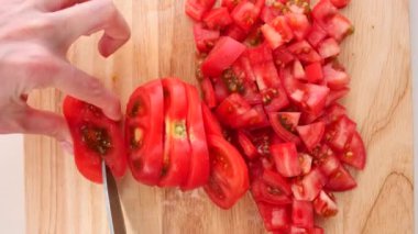 Kırmızı domatesler tahtada bir bıçakla kesilir. yakın plan