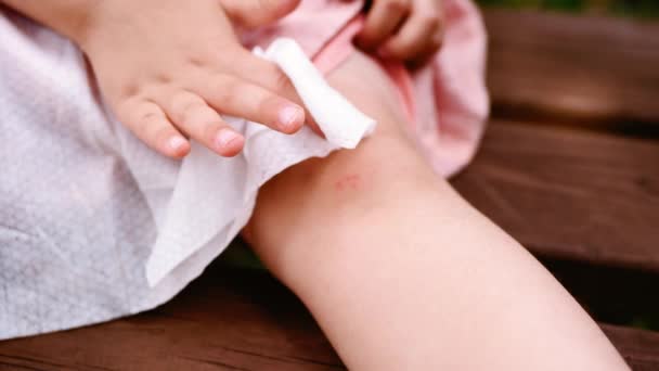 女の子はナプキンで彼女の皮をむいた膝を拭く — ストック動画