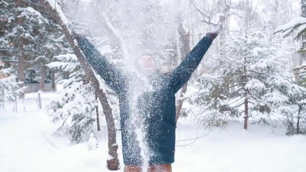 冬の森で幸せな若者が雪を上に投げる — ストック動画