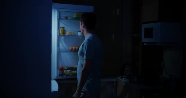 Мужчина Открывает Холодильник Ночью Берет Бутылку Воды Напитки — стоковое видео