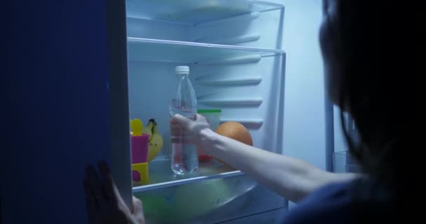 Женщина Ночью Открывает Холодильник Берёт Бутылку Воды Питьевая Вода — стоковое видео