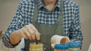 Genç bir kız kilden bir bardak ya da boyayla bir kupa boyuyor. Ortalama plan