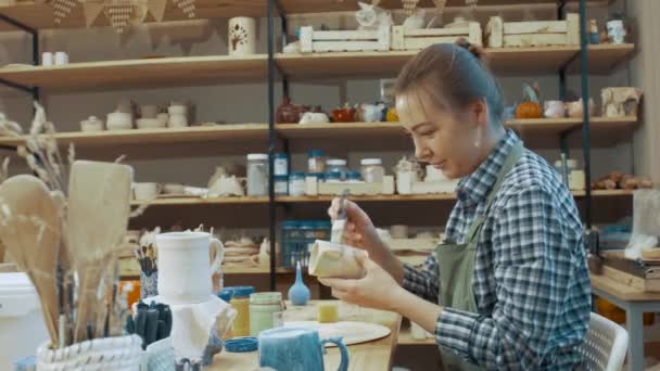 Meisje Schildert Een Handgemaakte Pot Met Verf Een Werkplaats Kijkend — Stockvideo