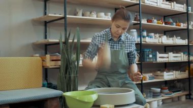 Kız çömlekçi bir çömlek heykeli yapıyor, atölyenin genel planı..