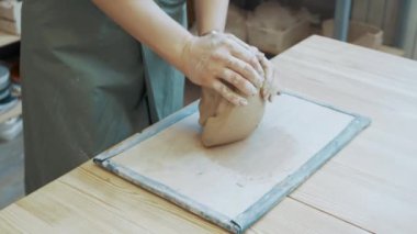 Bir kızın elleri çömlek çarkında çalışmak için kil yoğurur..