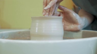 Çömlekçinin yetenekli elleri çömlekçi çarkında kil şekillendiriyor ve kilden kavanoz yontuyor.