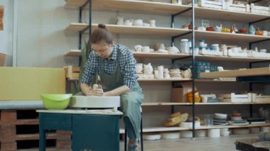 Bir atölyede çömlek tekeri üzerinde çalışan genç bir kız.