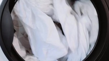 Çamaşır. Çamaşır makinesinin varilinde beyaz bir çarşaf dönüyor. yakın plan.