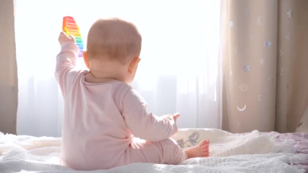 Mała Dziewczynka Siedzi Łóżku Przy Oknie Bawi Się Nową Zabawką — Wideo stockowe