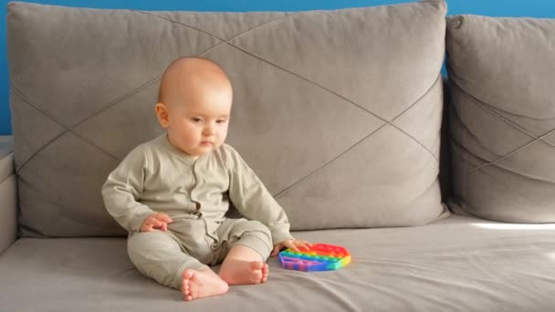 Uma Criança Pequena Está Sentada Sofá Com Brinquedo Pop Risos — Vídeo de Stock