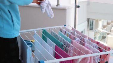 Bir kız kurutucuya renkli çamaşır asıyor. Çocuk eşyaları.