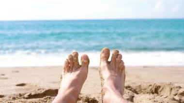 Erkek ayak parmakları hareket ediyor. Deniz ve kum arka planı.