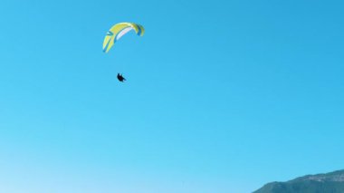 Paraşütçü mavi gökyüzünde uçuyor.