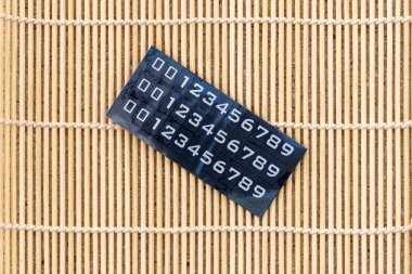 Bambu arka planında 0 'dan 9' a kadar olan plastik lastik etiket numaraları