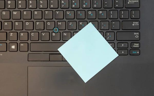 ノートパソコンのキーボードと青い空白の付箋 — ストック写真