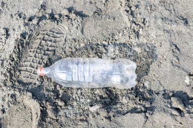 Kumsalda yatan boş plastik şişe çöpü. Plastik kirliliği kavramı