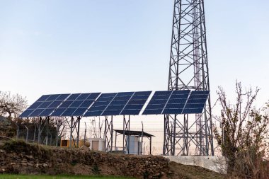 A cellular tower in the remote area powered by the solar panels clipart