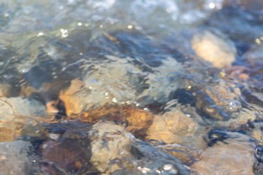 Flowing river water surface with big stone closeup