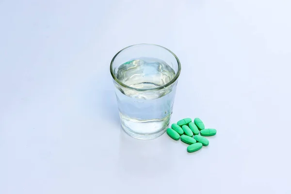 Pílulas Verdes Com Copo Água Sobre Fundo Isolado Branco — Fotografia de Stock